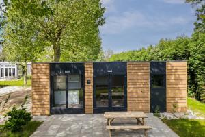 a small house with black windows and a picnic table at Cube I stijlvol en licht 4 persoons chalet in Zennewijnen