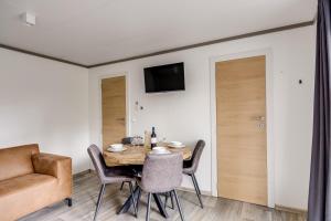a dining room with a table and chairs and a couch at Cube I stijlvol en licht 4 persoons chalet in Zennewijnen +44 photos