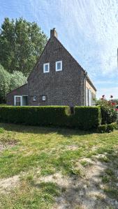 a large brick house with bushes in front of it at Villa Sint Anna in Sint Anna ter Muiden