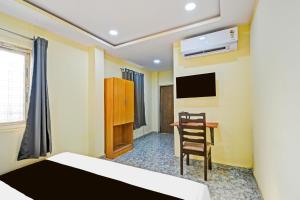 a bedroom with a bed and a chair and a desk at Hotel O Madlen in Hyderabad +21 photos