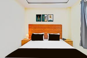 a bedroom with a white bed with a wooden headboard at Hotel O Madlen in Hyderabad