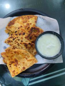 a black plate of food with a bowl of dip at Hotel Raj Bed And Breakfast in Agra