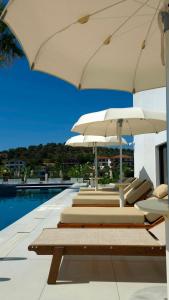 a row of lounge chairs with umbrellas next to a swimming pool at Hotel Zurich in Golem