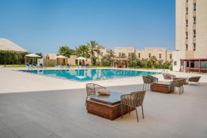 a swimming pool with chairs and a table and a tableasteryasteryasteryasteryastery at Premium Four Star Hotel by Blue Collection in Ras al Khaimah