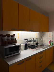 a kitchen with yellow cabinets and a microwave at Ines Apartment in Sarajevo