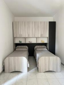 two beds in a room with white walls and cabinets at Appartamento Mina' in Adrano
