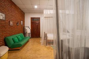 a room with a green couch next to a brick wall at Vihanga Village - Jungle retreat in Dambulla in Dambulla