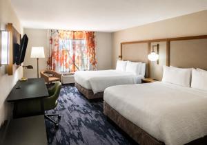 a hotel room with two beds and a desk at Fairfield By Marriott Middletown Monroe in Middletown