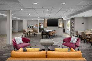 a lobby with chairs and a table and a dining room at TownePlace Suites Des Moines Urbandale in Johnston