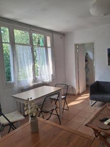 a living room with a table and chairs and windows at Maison charmante bordée de bambous in Auffargis