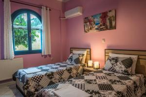 two beds in a room with pink walls at Myrovolos Guesthouse in Apolpaina