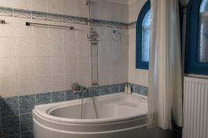 a white bath tub in a bathroom with a window at Myrovolos Guesthouse in Apolpaina +37 photos