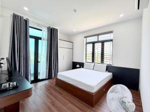 a bedroom with a bed and a desk and windows at The Haven Motel in Chú Cư