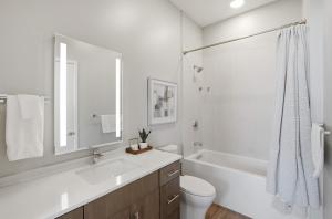 a white bathroom with a tub and a toilet and a sink at Illume 303 in Nashville +18 photos