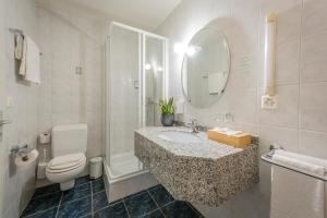 a bathroom with a sink and a toilet and a mirror at Hôtel du Cheval Blanc - City center in Bulle