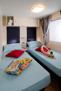 a bedroom with two beds with a stuffed animal laying on top at Camping San Michele in Moniga +57 photos