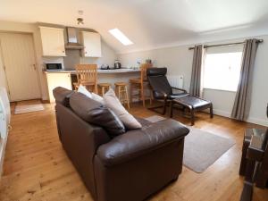 a living room with a leather couch and a kitchen at Pen Y Grisiau in Mold