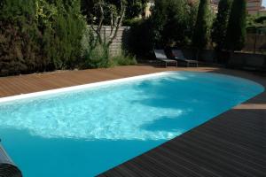 a large blue swimming pool with a wooden deck at Cabesthotes in Cabestany