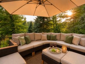 a patio with a couch and an umbrella at Sonnendeck - Familienzeit im Wald in Dahlen