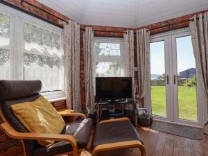 a living room with a couch and a tv and windows at Ty Haf in Mold