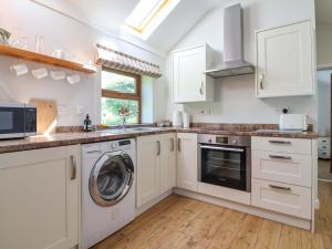 a kitchen with white cabinets and a washer and dryer at Ty Haf in Mold