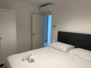 a white bed with a pair of shoes on it at Baden Resort Bašanija, Umag-with Sea View, Parking and 300m from the beach in Bašanija