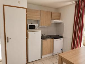 a small kitchen with a white refrigerator and a microwave at Soleiou in Salavas +2 photos