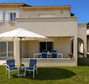 a patio with chairs and an umbrella in front of a house at Soleiou in Salavas