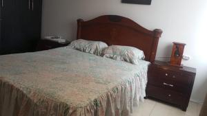 a bedroom with a bed with a wooden headboard and a dresser at Habitaciones Ciudad de la Luna Chia in Chía