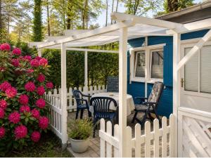 a blue house with a white fence and a table and chairs at Schwedenglück - Wald-Auszeit für 2 in Dahlen