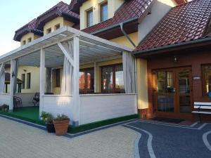 a house with a white pergola at Pensjonat Dom Latarnika in Grzybowo