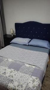 a bed with a blue headboard and two pillows at Habitaciones Ciudad de la Luna Chia in Chía