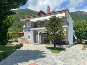 a white house with a tree in front of it at Ξενώνας Λίθος in Kato Loutraki