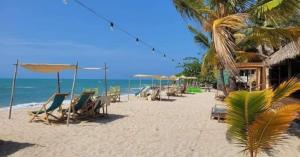 a beach with chairs and umbrellas and the ocean at Casa MACONDO BEACH HOUSE in Rincón