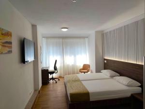 a bedroom with a bed and a desk and a television at Hotel Amstar Simeria in Simeria +48 photos