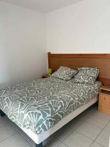a bed with a wooden headboard and two pillows at Résidence la Marquise in Trébas