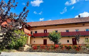 a building with red doors and a stone wall with flowers at Statek Soví Dvůr in Rabyně