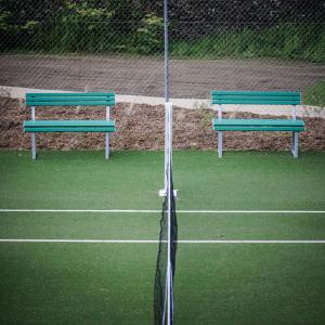 two green benches sitting on a tennis court at Domaine de Locguénolé & Spa - Relais & Chateaux in Kervignac