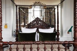 a wooden bed with pillows in a bedroom at Domaine de Locguénolé & Spa - Relais & Chateaux in Kervignac