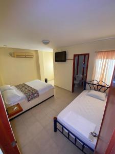 a hotel room with two beds and a television at Hotel Terranova SM in Santa Marta