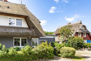 a house with a thatched roof and a garage at Freischwimmer in Wieck