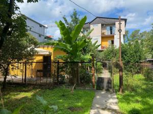 a fence with a tree in front of a building at Blue wave in Itʼkhvisi