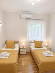 two beds in a small room with a window at Guest House Ankora in Skradin
