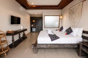 a bedroom with a bed and a desk and a television at Villa Silas Ubud Bali in Ubud