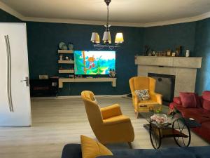 a living room with a couch and chairs and a tv at Blue wave in Itʼkhvisi
