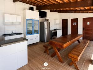a kitchen with a wooden table and a refrigerator at Pousada On the Beach - Aquiraz/CE in Aquiraz