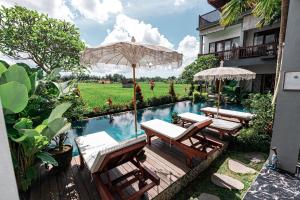 a pool with chairs and umbrellas next to a building at Villa Silas Ubud Bali in Ubud