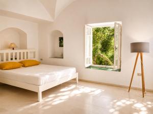 a white bedroom with a bed and a window at Maison de la Mer in Ḩammām al Ghazzāz +5 photos
