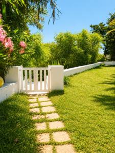 a garden with a white fence and grass at Maison de la Mer in Ḩammām al Ghazzāz