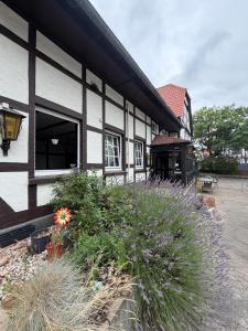 a black and white building with flowers in a yard at Heritage Timber Stay in Wendeburg